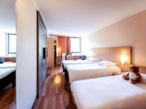 サルラ・ラ・カネダにあるIbis Sarlat Centreのベッド3台とベッドに座るテディベアが備わるホテルルームです。