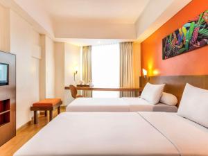 een hotelkamer met twee bedden en een raam bij Hotel Ibis Semarang Simpang Lima in Semarang