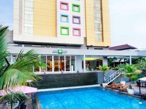 a hotel with a swimming pool in front of a building at Ibis Styles Solo in Solo