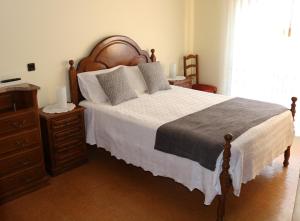 a bedroom with a large bed with a wooden headboard at Alojamento Correia in Caldelas