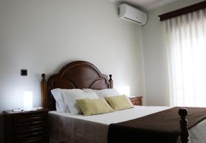 a bedroom with a large bed with a wooden headboard at Alojamento Correia in Caldelas