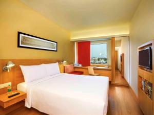 a hotel room with a white bed and a television at ibis Bengaluru Hosur Road - An Accor Brand in Bangalore