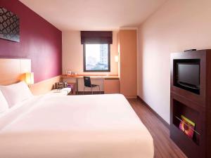a hotel room with a large bed and a tv at Ibis Bangkok Riverside in Bangkok