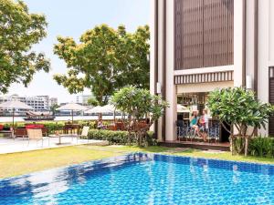a swimming pool in front of a building at Ibis Bangkok Riverside in Bangkok