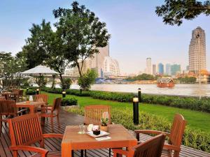 a patio with tables and chairs with a view of a river at Ibis Bangkok Riverside in Bangkok