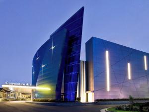 duży szklany budynek z niebieską fasadą w nocy w obiekcie Novotel Bangka Hotel & Convention Center w mieście Pangkal Pinang