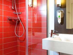 a red tile bathroom with a shower and a sink at Ibis Styles Lyon Centre - Gare Part Dieu in Lyon