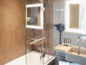 a shower with a glass door next to a sink at Novotel SPA Rennes Centre Gare in Rennes