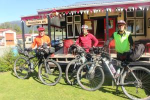 três homens de pé com as suas bicicletas em frente a um edifício em Blackball's Inn & 08 Cafe em Blackball