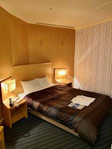 岐阜市にあるホテルグランヴェール岐山の大型ベッド1台とランプ2つが備わるホテルルームです。
