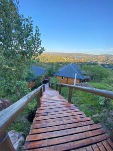 una passerella in legno che conduce a una cabina di Cabañas Los Álamos a Villa Carlos Paz