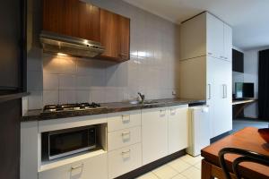 uma cozinha com armários brancos e um forno com placa de fogão em Riverview on Mount Street em Perth