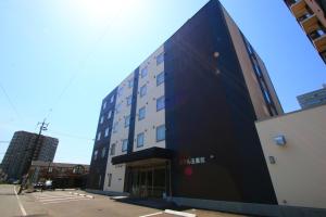 a tall building with a black facade on a street at Hotel Gobankan in Kumamoto