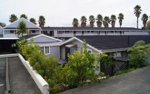 a house with a black roof with palm trees in the background at Walton Park Motor Lodge in Warkworth