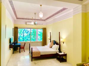 DubbīUmaid Palace - A Lakeside Resort - 25 minutes from Mehandipur Balaji - 20 minutes from Chand Baori Stepwell Abhaneri & 40 minutes from Bhangarh Fort的房间里有一张床和一张书桌的卧室