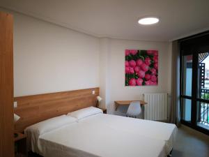 Apartamentos Gran Socaire de Noja في نوخا: غرفة نوم بسرير ابيض ولوحة تفاح