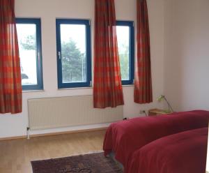 a bedroom with three windows with red curtains at Monteur und Messewohnung in Rodgau