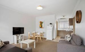 a living room with a couch and a table and a kitchen at Geelong Serviced Apartments in Geelong