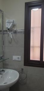 baño con lavabo blanco y ventana en Pensión La Montoreña, en Sevilla