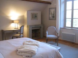 a bedroom with a bed with a fireplace and two chairs at Chambres d’Hôtes La Chance au Roy in Aigneville