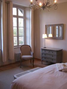a bedroom with a bed and a chair and a mirror at Chambres d’Hôtes La Chance au Roy in Aigneville