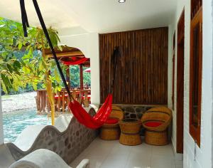 a porch with a hammock and some chairs at The Hangout@ EcoTravel in Bukit Lawang