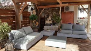 a patio with couches and a table on a wooden floor at L'Olivier Chez Mamé Marthe in Vallon-Pont-dʼArc
