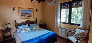 um quarto com uma cama com lençóis azuis e duas janelas em Hotel Rural El Camino em Candeleda