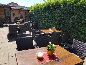 eine Terrasse mit Tischen, Stühlen und einer Hecke in der Unterkunft Hotel - Restaurant Veldscholten in Lingen