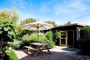 a picnic table with an umbrella on a patio at B&B De Sprokkeltuin in Beuningen