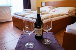 a bottle of wine and two wine glasses on a table at Penzion pod Kraví horou in Bořetice