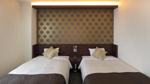 dos camas sentadas una al lado de la otra en una habitación en Hotel Annex Inn, en Shinhidaka