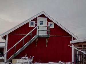 a red barn with a staircase on the side of it at Lägenhet på landet in Torsby