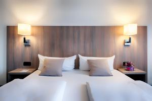 a large white bed with two pillows and two lights at ACHAT Hotel Bochum Dortmund in Bochum +24 photos