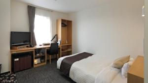 a hotel room with a bed and a desk with a television at Hotel Annex Inn in Shinhidaka