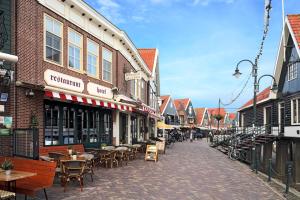 eine Stadtstraße mit Tischen, Stühlen und Gebäuden in der Unterkunft Hotel Cafe Restaurant Van Den Hogen in Volendam