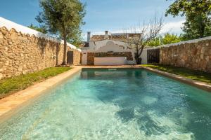 a swimming pool in front of a stone wall at Villa Monte Algarvio - Private Heated Pool - wifi in Tunes