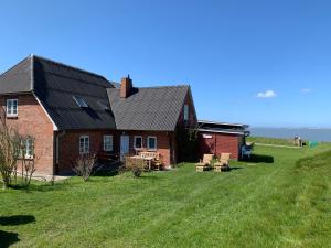 a house on the side of a grassy hill at Kapitänshaus Meerblick in Langeneß