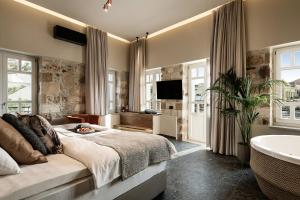 una camera con un grande letto e una vasca da bagno di Divino Suites Chania a Chania