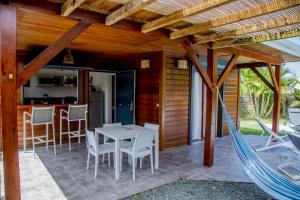 eine Terrasse mit einer Hängematte sowie einem Tisch und Stühlen in der Unterkunft Fleurs de canne piscines privées in Le Moule