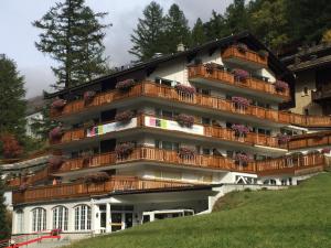 un edificio con balconi e fiori di Artist Apartments & Hotel Garni a Zermatt