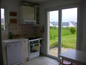 a kitchen with a stove and a view of a yard at Maison d'Aude in Brignogan-Plage