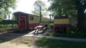una pequeña casa con una mesa de picnic y un banco de picnic en La Roulotte CHAINOUX, en Bains-sur-Oust