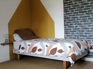 een bed in een kamer met een bakstenen muur bij séjour littoral 4 pers proche mer in Clohars-Carnoët