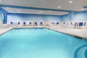uma grande piscina com cadeiras e mesas e cadeiras num edifício em Holiday Inn Express Boston Brockton, an IHG Hotel em Brockton
