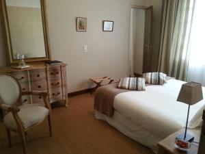 um quarto com uma cama, uma cadeira e um espelho em MAISON DE MARQUAY-MAISON D'HOTES em Marquay