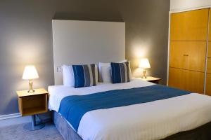 1 cama grande en una habitación de hotel con 2 lámparas en The Angel Hotel, en Cardiff