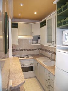a large kitchen with white cabinets and a sink at Nerja Villas-Capistrano in Nerja
