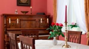 a dining room with a table with a candle and red roses at Villa Hierschel Droyßig in Droyßig