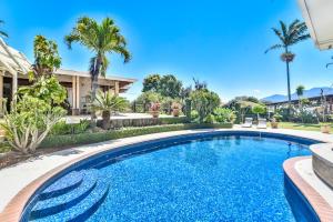 a swimming pool in front of a house with palm trees at La Riviera Hotel in San Antonio